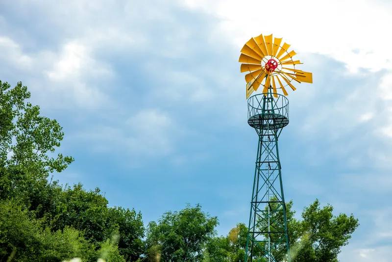PE wind-powered water pump with a yellow wind wheel against a blue sky